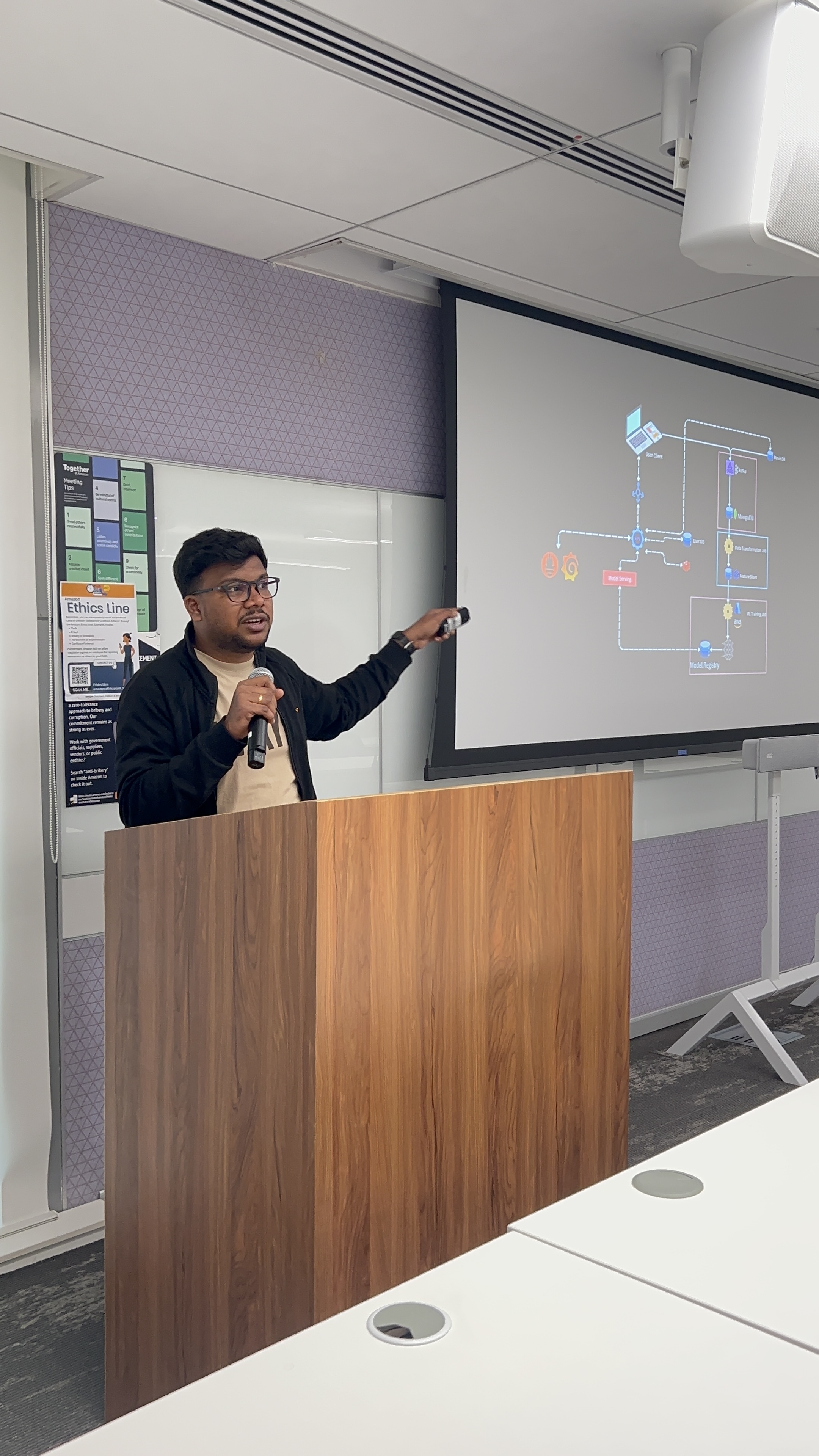 Shabul Hussain Abdul presenting a tech talk at podium with microphone and architecture diagram